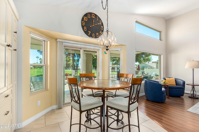 dining area with light hardwood / wood-style flooring, a notable chandelier, high vaulted ceiling, and a wealth of natural light