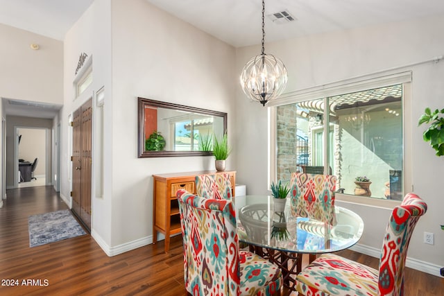 dining area featuring dark wood-type flooring, vaulted ceiling, and a notable chandelier