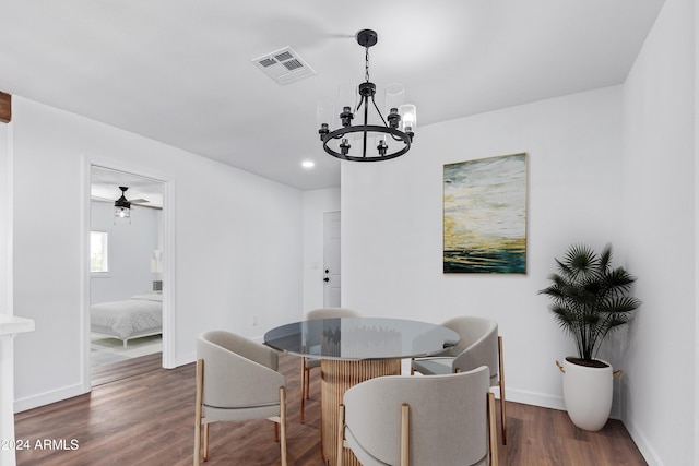 dining space with ceiling fan with notable chandelier and dark wood-type flooring