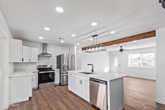 kitchen featuring sink, wall chimney exhaust hood, an island with sink, appliances with stainless steel finishes, and white cabinetry