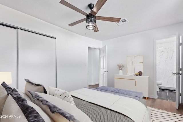 bedroom with ensuite bathroom, ceiling fan, dark wood-type flooring, and a closet