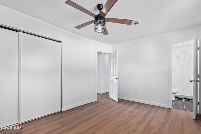 unfurnished bedroom with ensuite bathroom, a closet, dark wood-type flooring, and ceiling fan