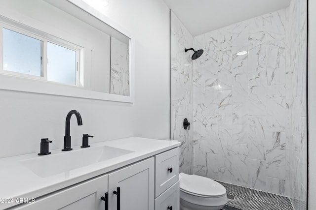 bathroom with a tile shower, vanity, and toilet