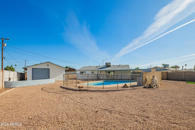 exterior space with a fenced in pool, a patio area, an outbuilding, and a garage