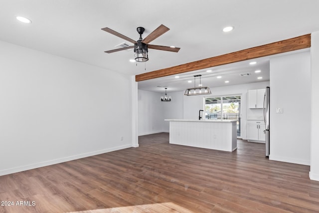 unfurnished living room with beam ceiling, ceiling fan, and dark wood-type flooring