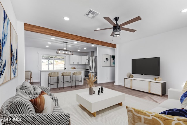 living room featuring beam ceiling, light hardwood / wood-style flooring, and ceiling fan