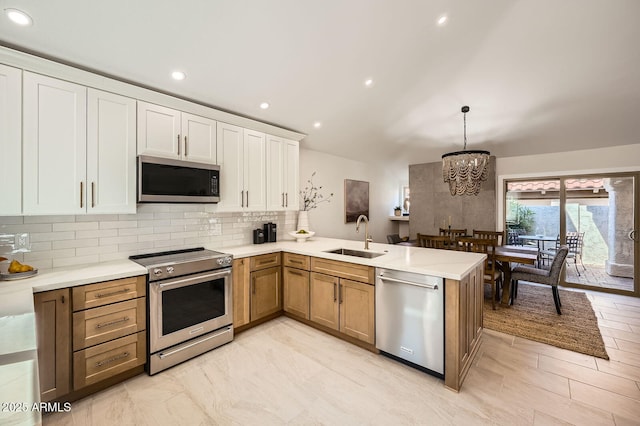 10023 E Sunnyslope Ln, Scottsdale, AZ 85258 - kitchen featuring appliances with stainless steel finishes, a sink, a peninsula, vaulted ceiling, and decorative backsplash