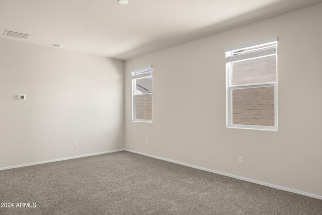 spare room with carpet flooring, baseboards, and visible vents