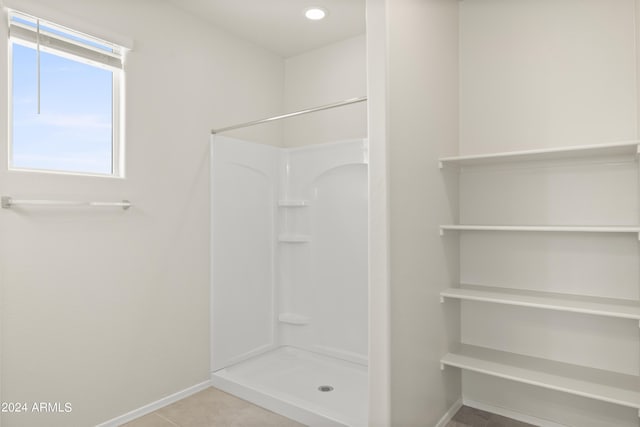 bathroom featuring tile patterned flooring, baseboards, and walk in shower