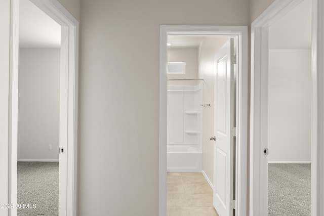 hallway with light tile patterned floors, light colored carpet, and baseboards