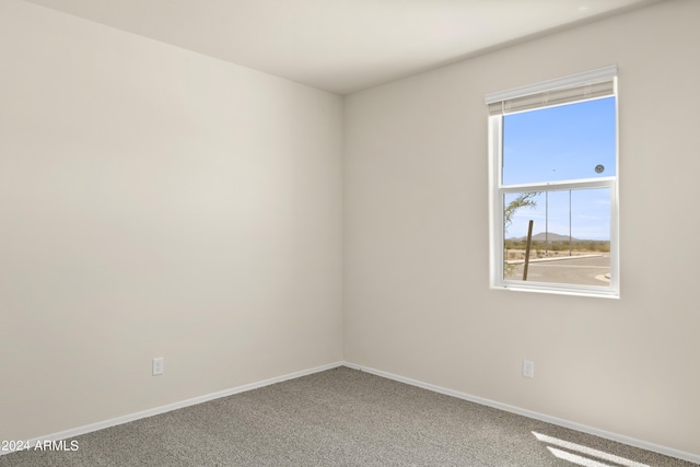 spare room featuring carpet flooring and baseboards