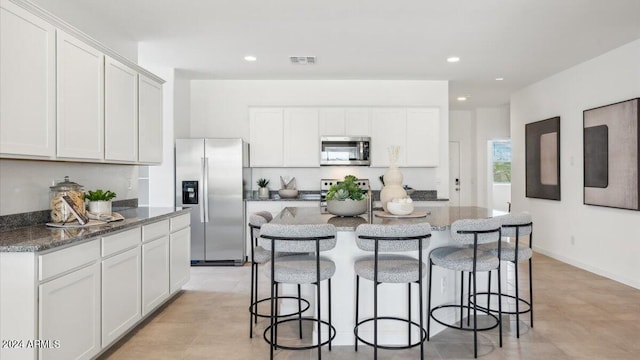 kitchen featuring a kitchen bar, visible vents, white cabinetry, and stainless steel appliances