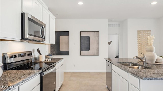 kitchen featuring dark stone counters, recessed lighting, a sink, stainless steel appliances, and white cabinetry