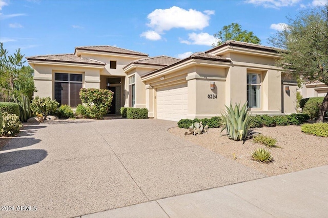 prairie-style home featuring a garage, driveway, and stucco siding