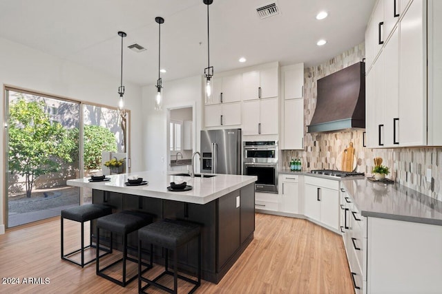 kitchen with stainless steel appliances, visible vents, white cabinets, custom exhaust hood, and tasteful backsplash