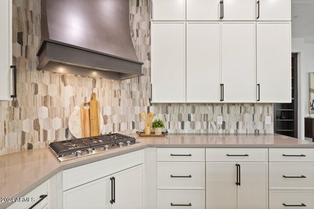 kitchen featuring white cabinets, custom exhaust hood, and tasteful backsplash