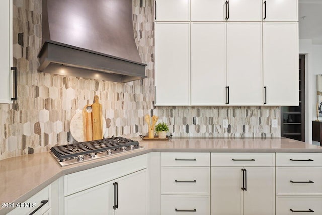 kitchen with stainless steel gas cooktop, light countertops, white cabinetry, and custom range hood