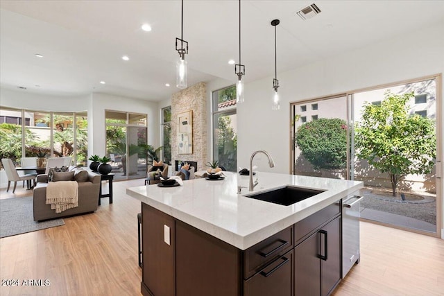 kitchen featuring dark brown cabinetry, a sink, visible vents, open floor plan, and a wealth of natural light