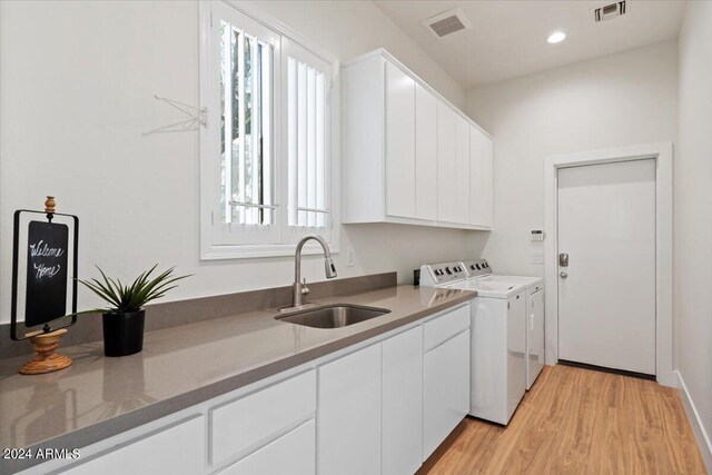 laundry room featuring a healthy amount of sunlight, light hardwood / wood-style floors, independent washer and dryer, and sink