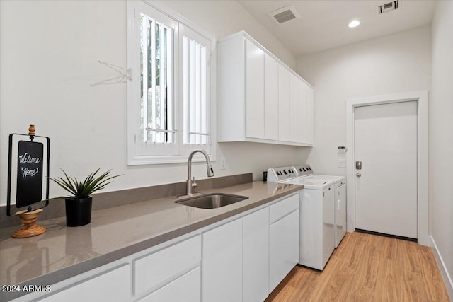 washroom featuring cabinet space, visible vents, washer and dryer, a healthy amount of sunlight, and a sink