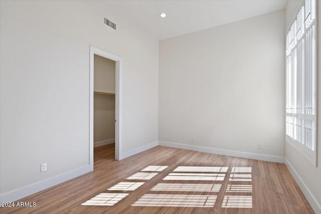 unfurnished bedroom featuring lofted ceiling, a closet, light hardwood / wood-style floors, and a spacious closet