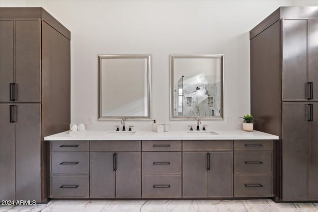 bathroom with marble finish floor, double vanity, walk in shower, and a sink