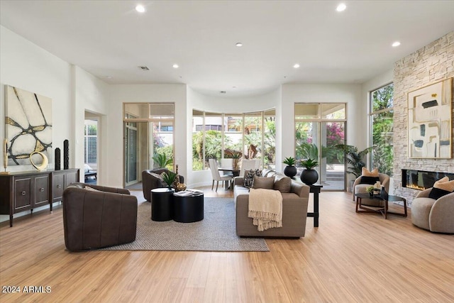 living area with recessed lighting, wood finished floors, and a stone fireplace