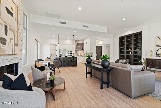 living room with a fireplace, visible vents, and light wood-style floors