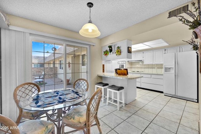 dining space with light tile patterned floors, a textured ceiling, and visible vents