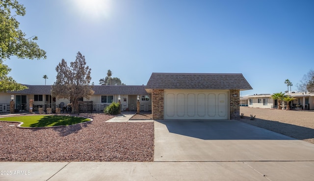 view of front of house featuring mansard roof, a shingled roof, fence, a garage, and driveway