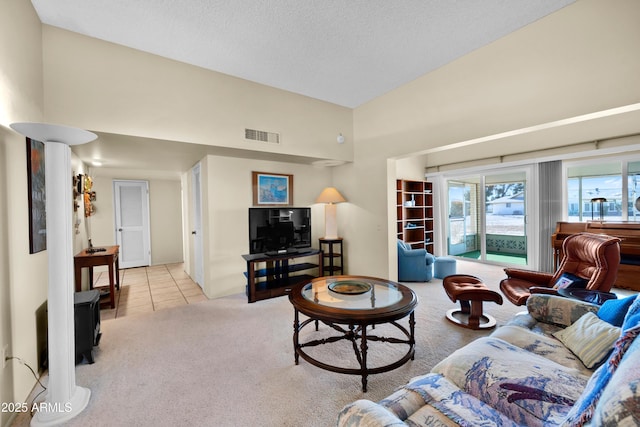 carpeted living area with high vaulted ceiling, tile patterned flooring, visible vents, and a textured ceiling