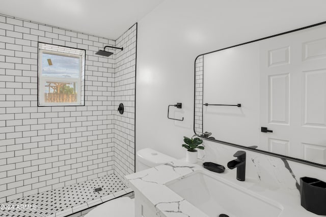 bathroom featuring a tile shower, vanity, and toilet