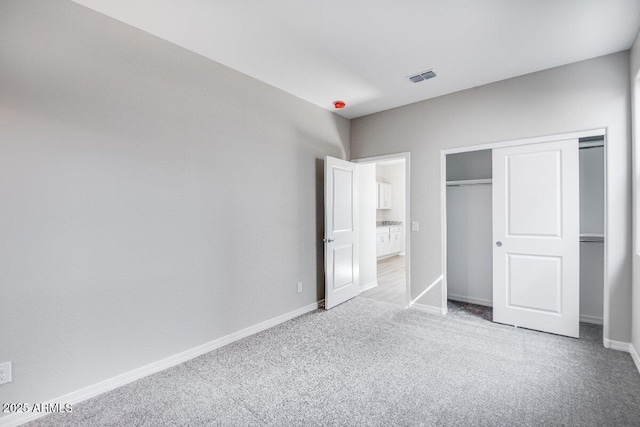 unfurnished bedroom featuring visible vents, a closet, baseboards, and carpet flooring