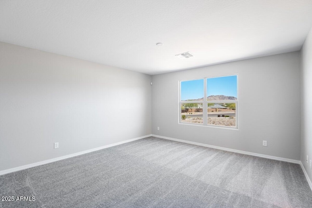 carpeted spare room featuring visible vents and baseboards