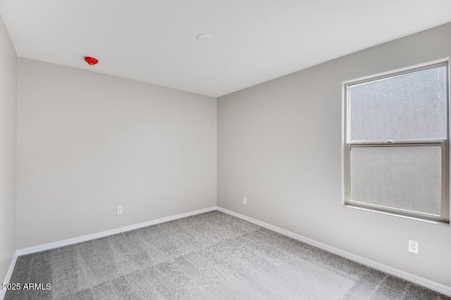 carpeted empty room featuring baseboards