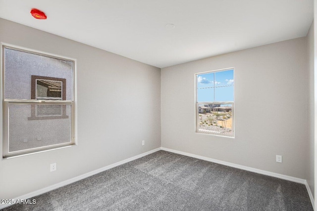 carpeted empty room featuring baseboards