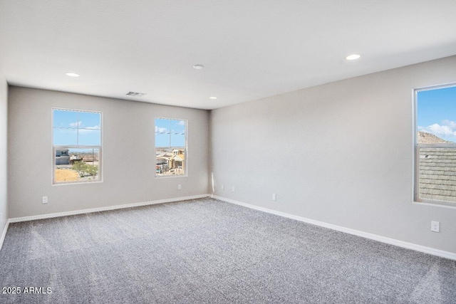 unfurnished room featuring carpet, visible vents, and baseboards