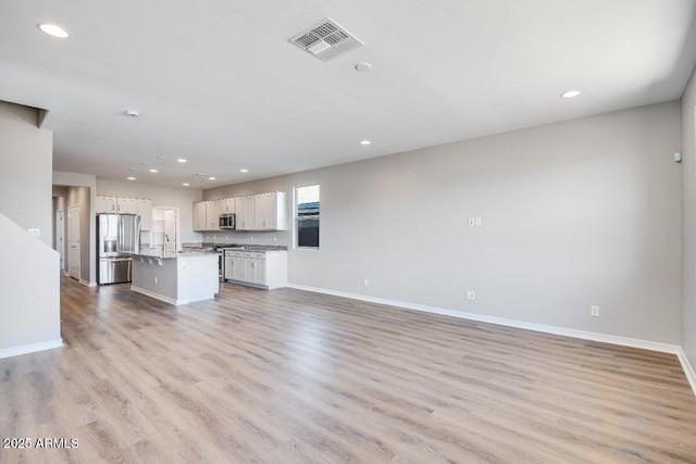 unfurnished living room featuring recessed lighting, light wood-type flooring, visible vents, and baseboards