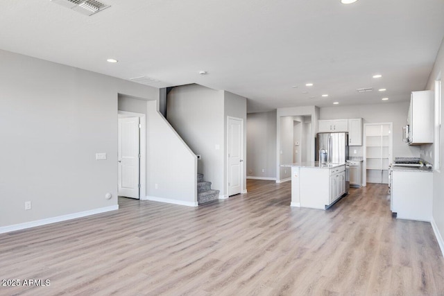 kitchen featuring light wood-style floors, a kitchen island with sink, visible vents, and open floor plan