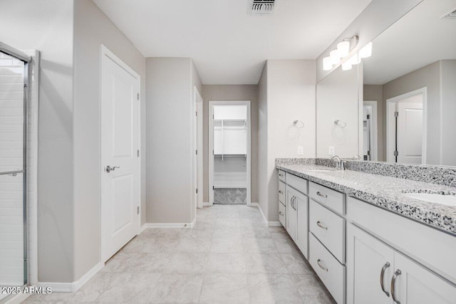 bathroom with a stall shower, visible vents, a walk in closet, and a sink