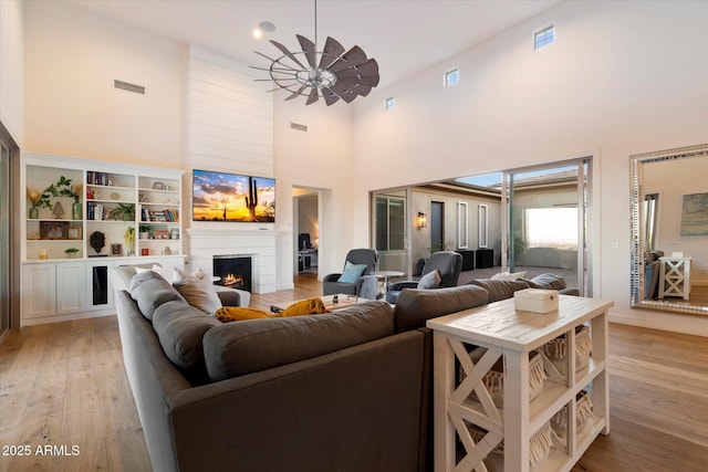 6535 W Gold Mountain Pass, Phoenix, AZ 85083 - living room featuring a high ceiling, ceiling fan, light wood-style floors, a large fireplace, and visible vents