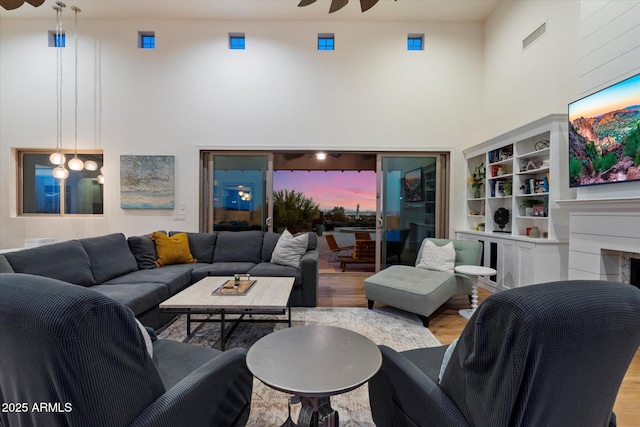 6535 W Gold Mountain Pass, Phoenix, AZ 85083 - living area with a high ceiling, a fireplace, a ceiling fan, wood finished floors, and visible vents