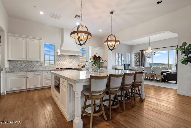 6535 W Gold Mountain Pass, Phoenix, AZ 85083 - kitchen with backsplash, a chandelier, a kitchen island with sink, and light wood-type flooring