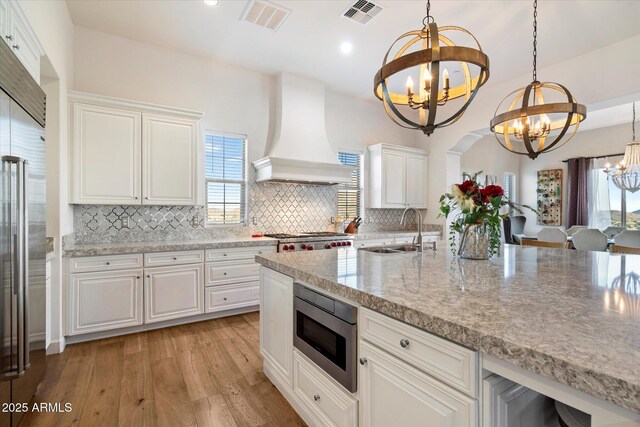 6535 W Gold Mountain Pass, Phoenix, AZ 85083 - kitchen featuring an inviting chandelier, a sink, built in appliances, custom range hood, and visible vents