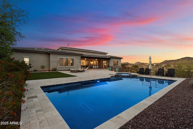 6535 W Gold Mountain Pass, Phoenix, AZ 85083 - back of property at dusk featuring a patio, a pool with connected hot tub, fence, and stucco siding