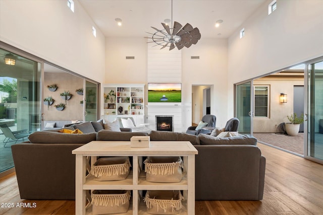 6535 W Gold Mountain Pass, Phoenix, AZ 85083 - living area with visible vents, a warm lit fireplace, wood finished floors, and a towering ceiling