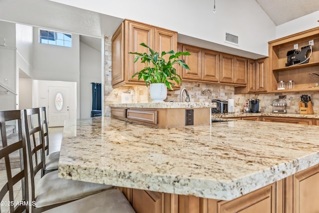 7949 W Pershing Ave, Peoria, AZ 85381 - kitchen featuring high vaulted ceiling, tasteful backsplash, light stone countertops, a peninsula, and open shelves