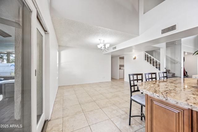 7949 W Pershing Ave, Peoria, AZ 85381 - kitchen featuring brown cabinetry, a chandelier, a textured ceiling, light tile patterned flooring, and light stone counters