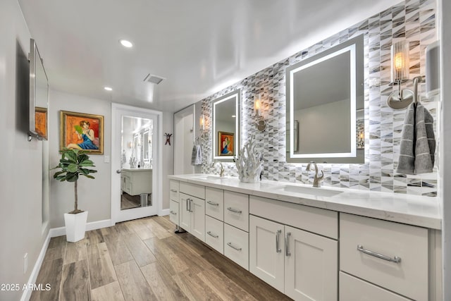 3109 E Sierra Madre Way, Phoenix, AZ 85016 - bathroom featuring double vanity, wood finished floors, tasteful backsplash, and recessed lighting