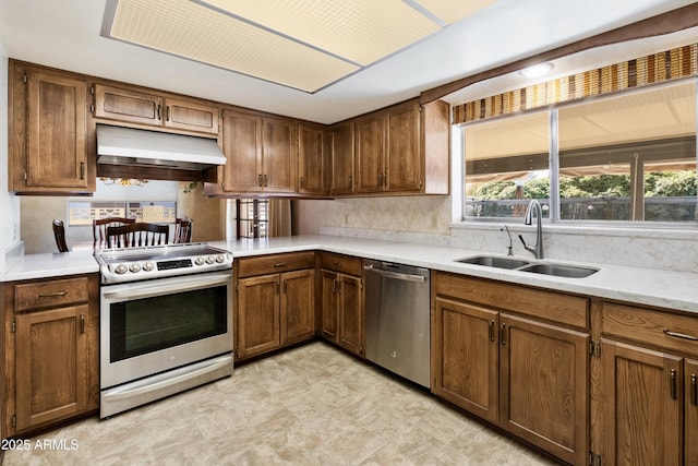 kitchen with brown cabinetry, appliances with stainless steel finishes, extractor fan, and a sink